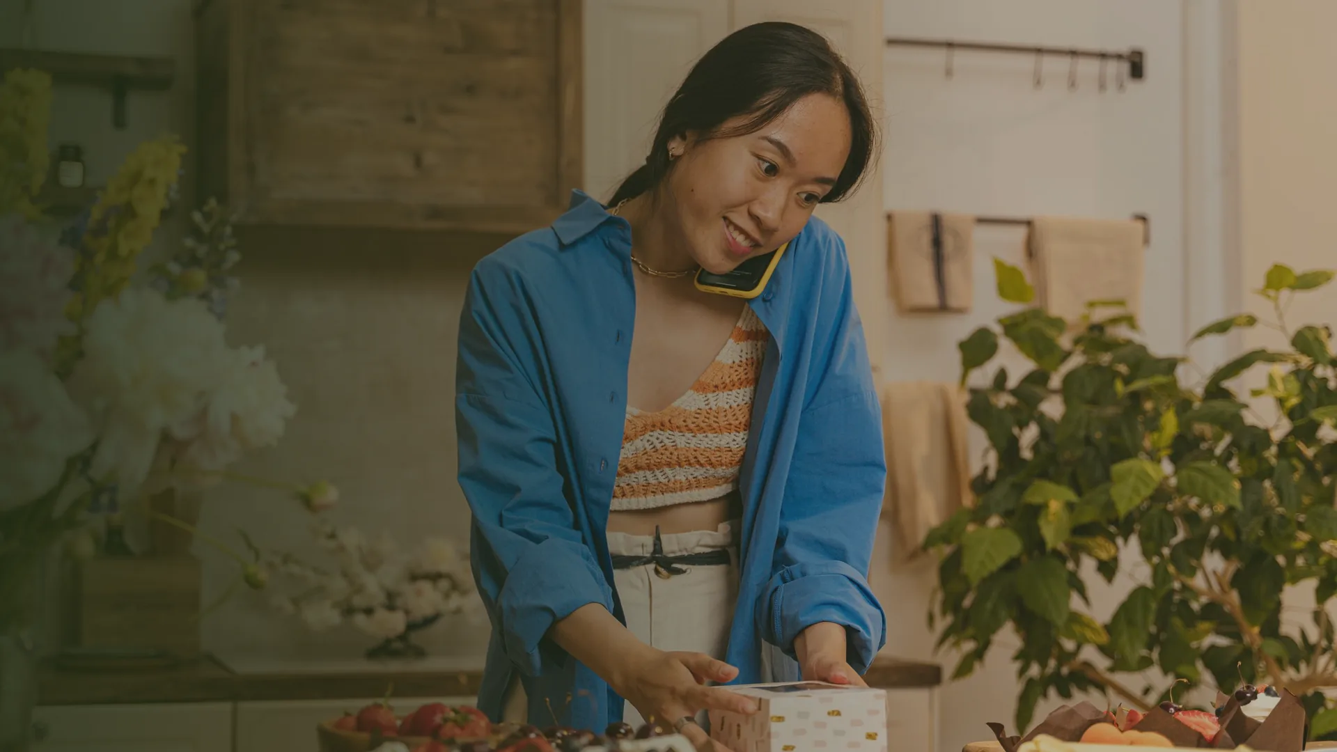 Chủ tiệm bánh vừa nghe điện thoại vừa đóng hộp bánh cho khách